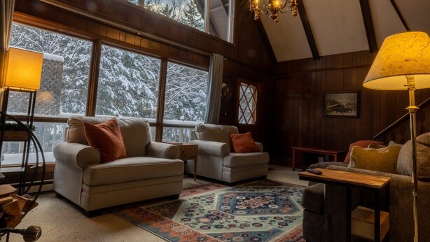 A cozy living room with a high ceiling, large windows, and a chandelier. - Spacious Chalet, Skiing 5 Minutes to Jay Peak, Vermont! (Montgomery)
