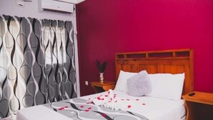 Une chambre d’hôtel avec un lit, une table de chevet et une tête de lit en bois.