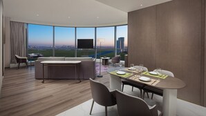 A modern hotel room with a dining area, large windows offering a city view, and a flat-screen TV. - La Quinta by Wyndham Shanxi Xiaohe Xincheng (Taiyuan)