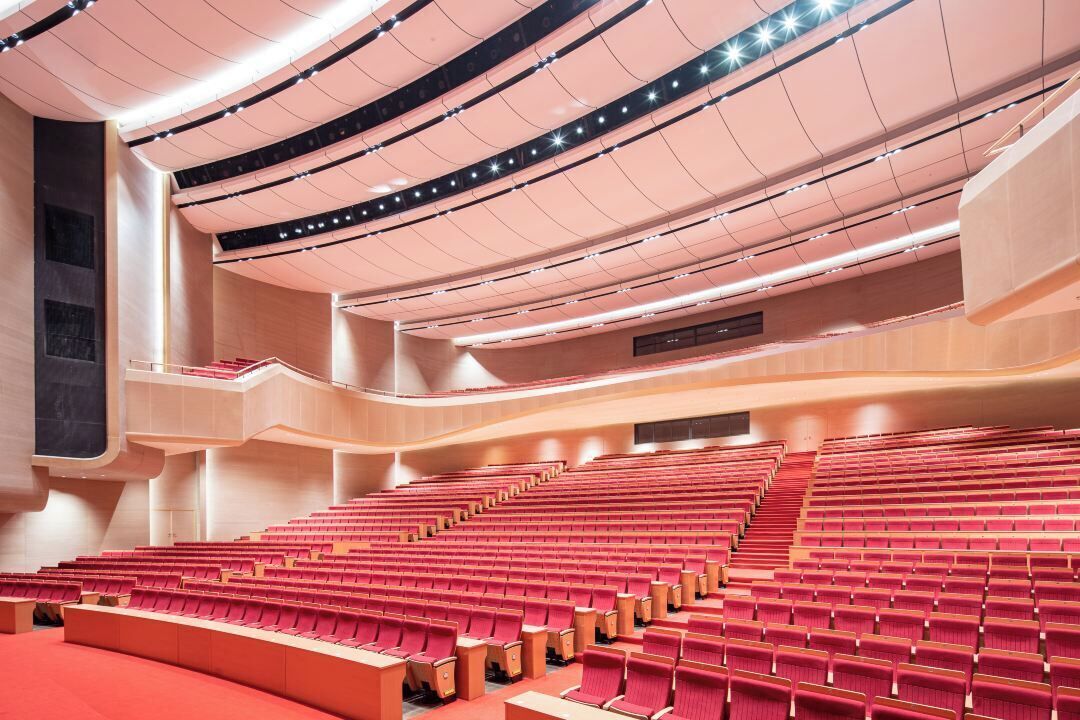 Un auditorio moderno con asientos escalonados y un techo curvo.