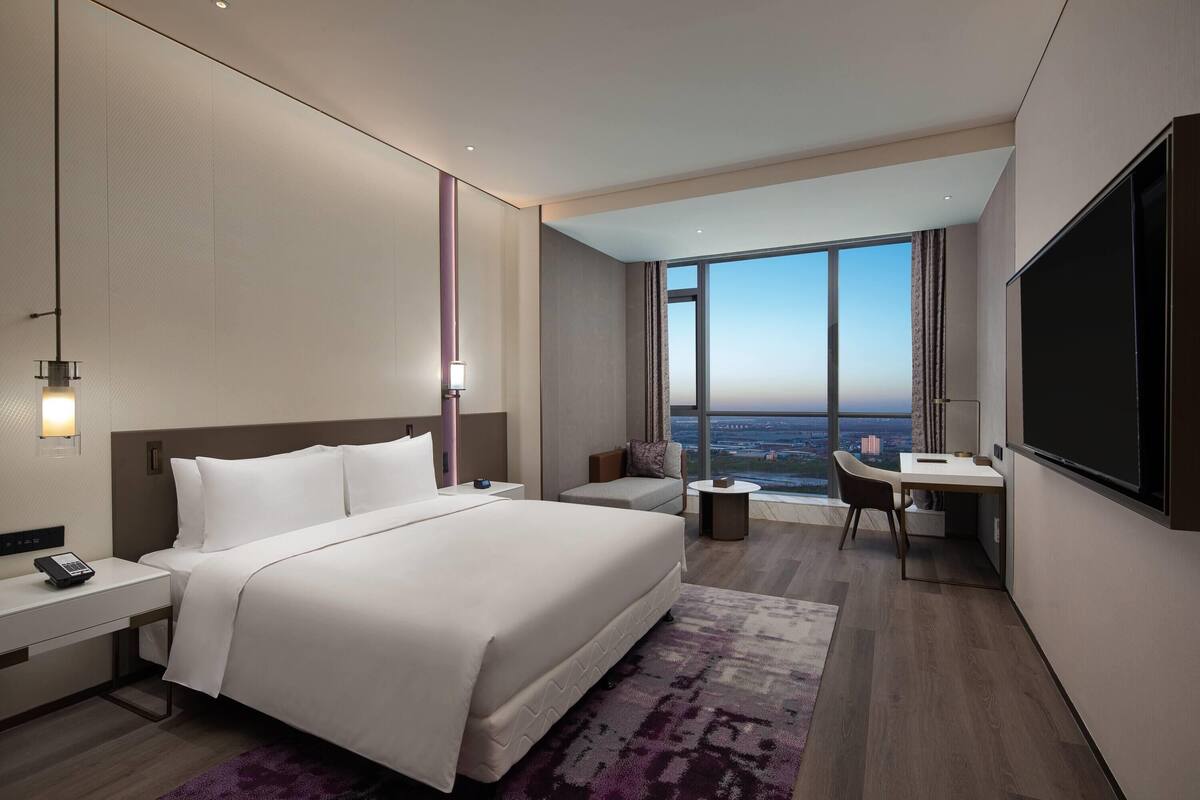 Une chambre d’hôtel moderne équipée d’un grand lit, d’un bureau, d’une chaise et d’un téléviseur.