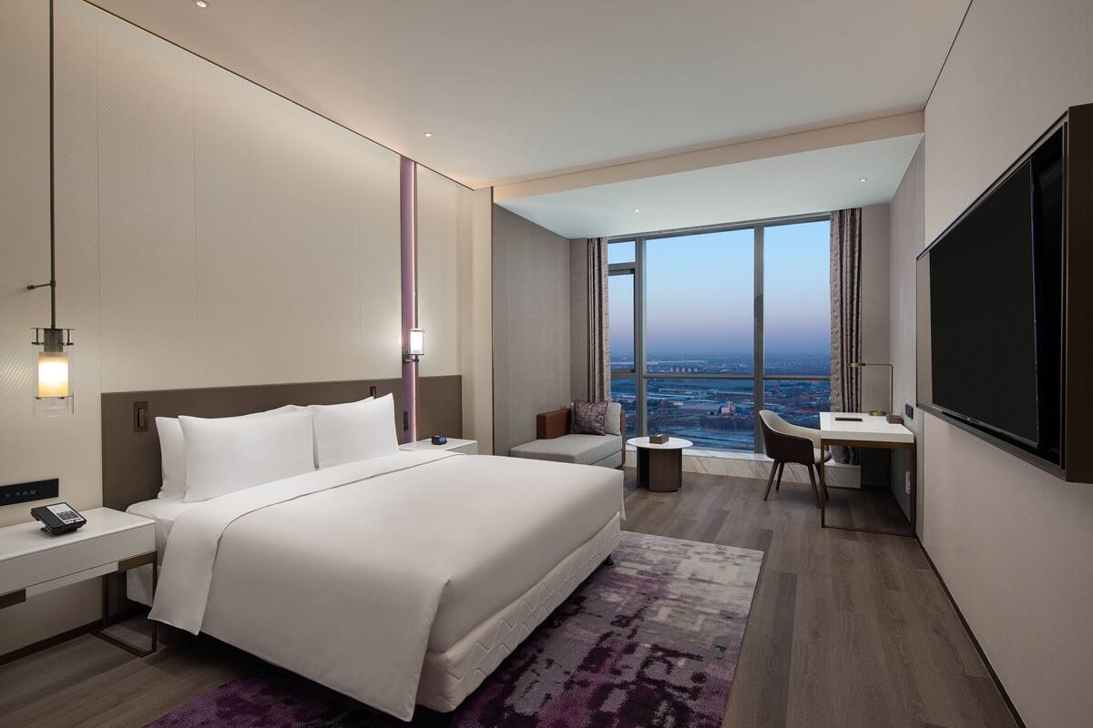 Une chambre d’hôtel moderne avec un grand lit, un bureau et une télévision.