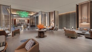 A spacious lobby with a central seating area, a large vase with orange flowers, and a modern interior design.