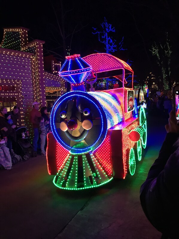 Un tren muy iluminado con un frente circular y una parte superior azul, rodeado de gente.