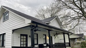 Een twee verdiepingen tellend huis met een overdekte veranda, nummer 43, met een zitgedeelte met tafels en stoelen.