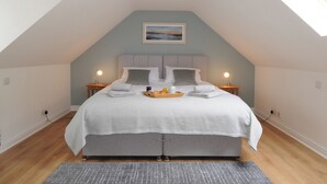 Une chambre à coucher comprenant un lit, deux tables de chevet, une commode, une fenêtre et un luminaire au plafond.