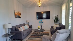 A living room with a sofa, armchair, TV, and decorative items.