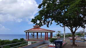 A gazebo with a red roof overlooking a coastal area.