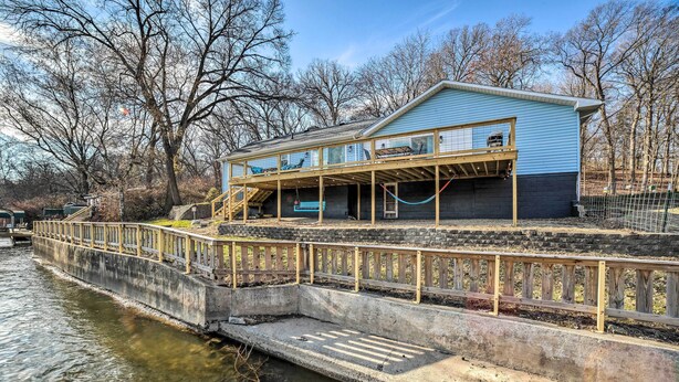 Ein Haus mit überdachter Veranda und einer Betonsteganlage, die sich ins Wasser erstreckt.