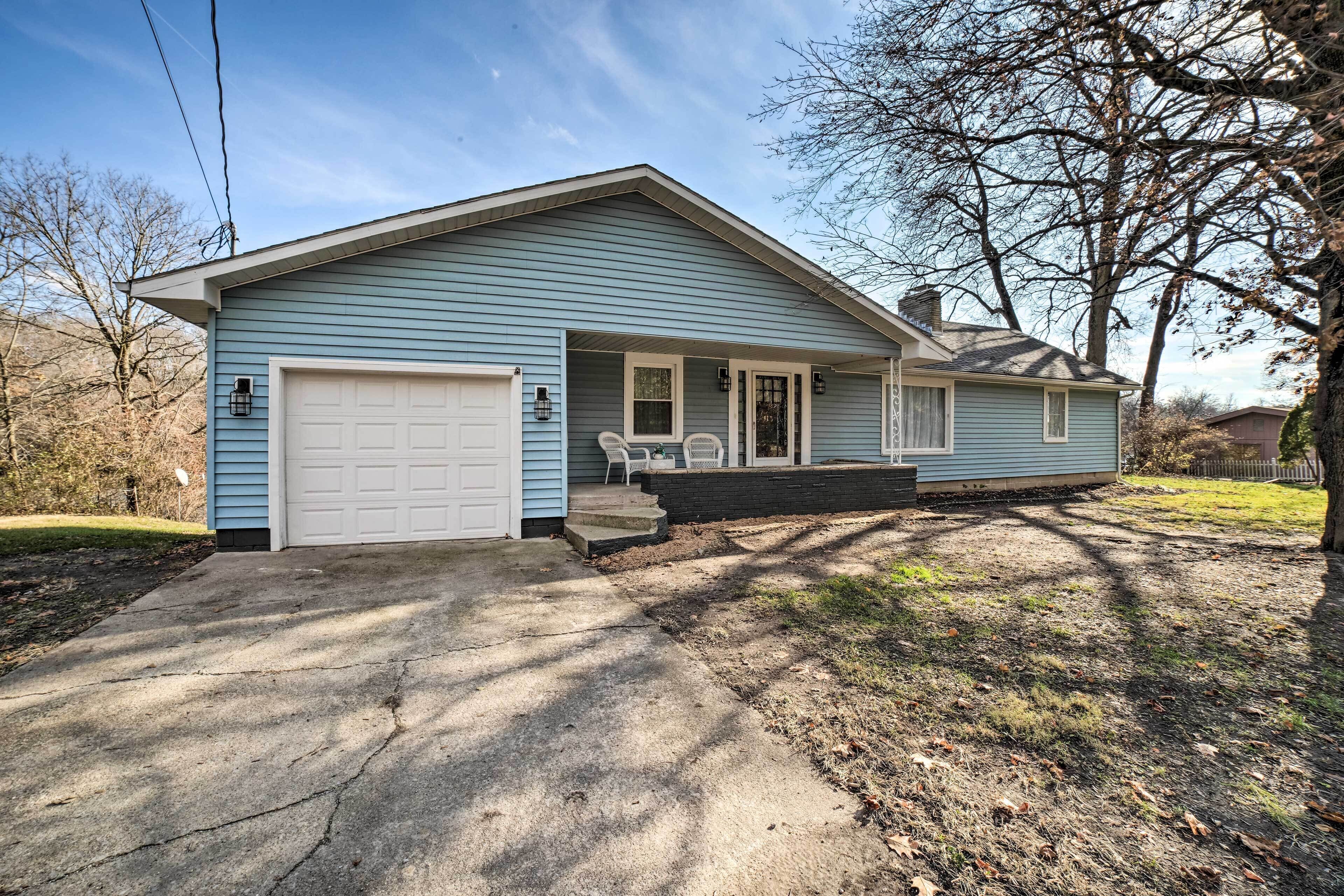 A single-story house with a garage, a front porch with a table and chairs, and a small front yard.