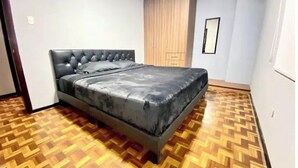 A bedroom with a bed, wooden parquet flooring, a wardrobe, and a mirror. - Lovely 2-Bedroom Rental Unit in Quito (QUITO)
