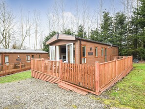 A wooden cabin with a deck, a TV, and a sign that reads "Marley Lodge."