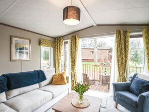 A cozy living room with a sofa, a chair, a coffee table, and a view of the outside. - As soon as you arrive at Daisy Bank Caravan Park, you feel instantly rested. (Montgomery)