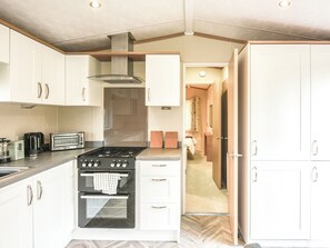 A modern kitchen with white cabinets, a gas stove, a toaster, and a coffee maker.
