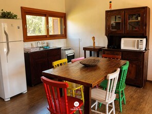 A kitchen with a wooden table, chairs, a refrigerator, a stove, and a microwave.