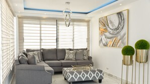 Una sala de estar moderna con un sofá modular, un reposapiés y plantas decorativas.