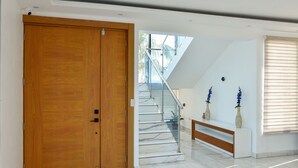 Un interior moderno con una puerta doble de madera, una escalera de mármol y un banco con jarrones.