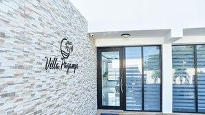Un edificio moderno con pared de textura pétrea y un logotipo que dice "Villa Playa Mambo".