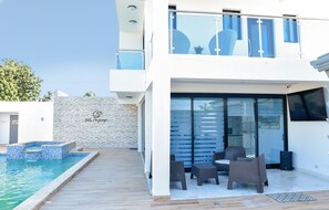 Une villa moderne dotée d’une piscine, d’un espace salon extérieur et d’un mur en pierre.