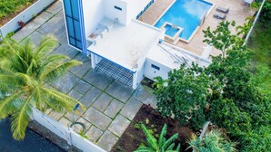 Una casa moderna con piscina, un patio y abundante vegetación.