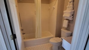 A bathroom with a shower, toilet, and a towel rack.