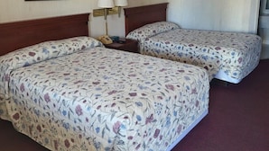 A hotel room with two beds, a nightstand with lamps, and framed artwork on the walls.
