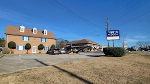 A WHITS INN building with a parking lot and a grassy area in front.