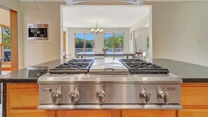 A kitchen with a double gas range, a built-in water dispenser, and a view of the outdoors through large windows. - Angel Bear Chalet- Private Lake/Beach/Sauna/Hot Tub/Gym/Firepit/Float Trampoline (Peru)