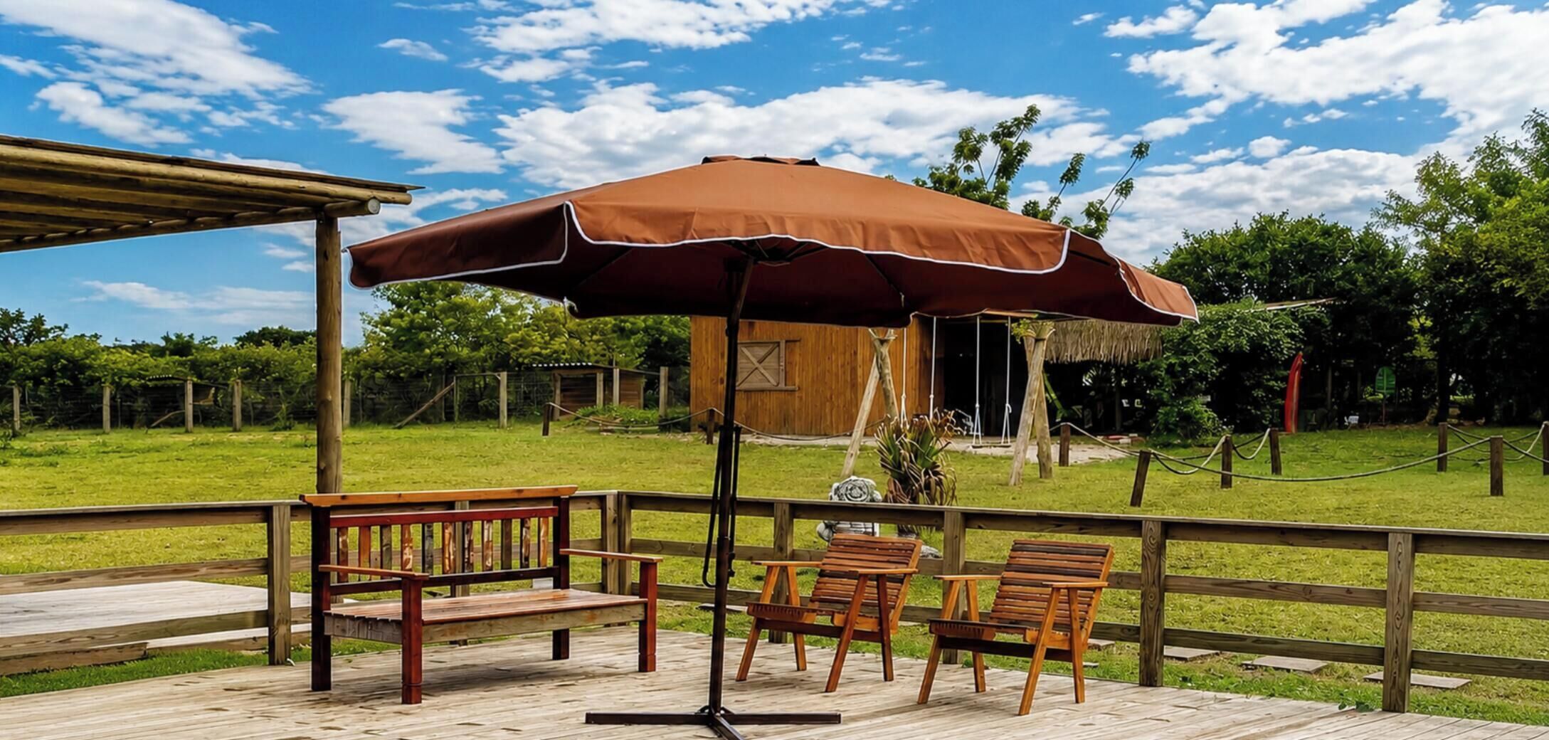 An outdoor patio with wooden furniture and a large umbrella.