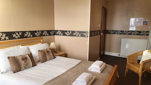 Ein Hotelzimmer mit Bett, Stuhl, Nachttisch, Lampe und Heizkörper.
