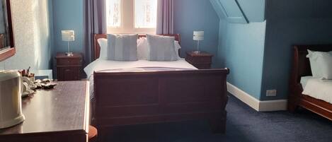 Un dormitorio con una cama, una mesita de noche, un aparador y una ventana con cortinas.