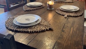 Une table à manger dressée avec des assiettes, une bougie, et une cheminée en arrière-plan.