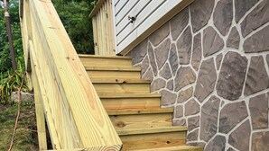 Un escalier en bois, avec un mur de pierre à côté.