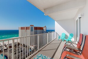 Enjoy the ocean view from this balcony with a bathtub, two chairs, and a single chair.
