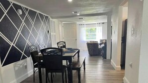 A dining area with a black and white geometric wall design, a wooden dining table with chairs, and a patterned rug on the floor. - Close to Disney and the Beaches Full House 3/3 (Orlando)