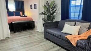 A modern bedroom with a bed, a bench, a sofa, and a potted plant. - Close to Disney and the Beaches Full House 3/3 (Orlando)