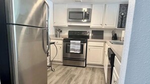A kitchen with white cabinets, stainless steel appliances, and a wooden floor. - Close to Disney and the Beaches Full House 3/3 (Orlando)