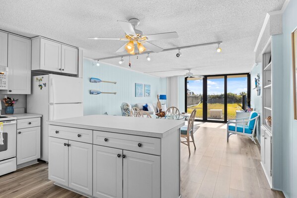 Enjoy meals in this well-equipped kitchen with a central island, dining area, and large window offering a view of the outdoors.