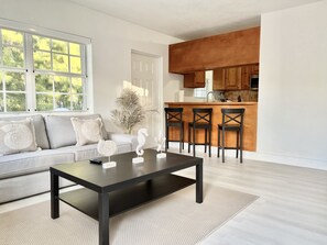 Relax in a serene space with a view of lush greenery, featuring a comfortable sofa and sleek coffee table.