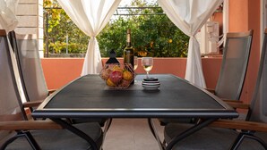 A table set for two with a bottle of wine, a glass, and a fruit basket. - Apartment Dionis Domus - Two Bedroom Apartment with Swimming Pool (Vela Luka)
