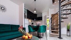 A modern living room with a green sofa, a round table with fruit, and a staircase. - Apartment Dionis Domus - Two Bedroom Apartment with Swimming Pool (Vela Luka)
