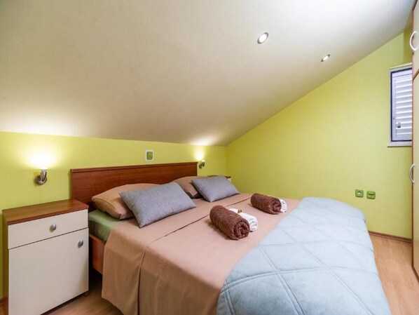 A bedroom with a bed, nightstands, and a window with blinds.