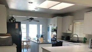A modern kitchen with a central island, bar stools, and a dining area. - Beautiful 3,000 Sq Ft Tropical Oasis (El Cajon)