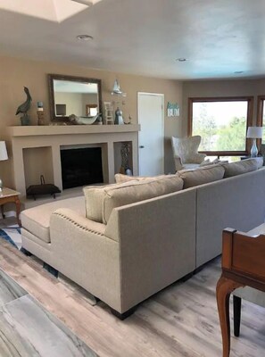 A living room with a beige sofa, a fireplace, and a large window.