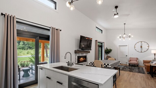 A modern kitchen with a central island, a fireplace, and a dining area with a checkered tablecloth. - Luxury Retreat in the Mountains! (Thornton)