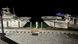 A nighttime marina with boats docked, a wooden walkway, and a person standing in the center.