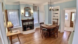 Un comedor con una mesa y sillas de madera, una chimenea y un candelabro.