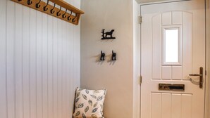 Un couloir avec un banc en bois, un porte-manteau et une porte dotée d’une fenêtre.