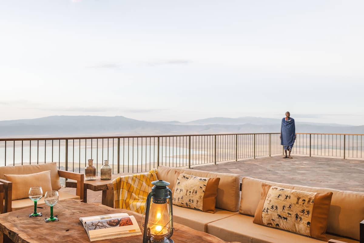 A terrace with a sofa, a wooden table, and a lantern.