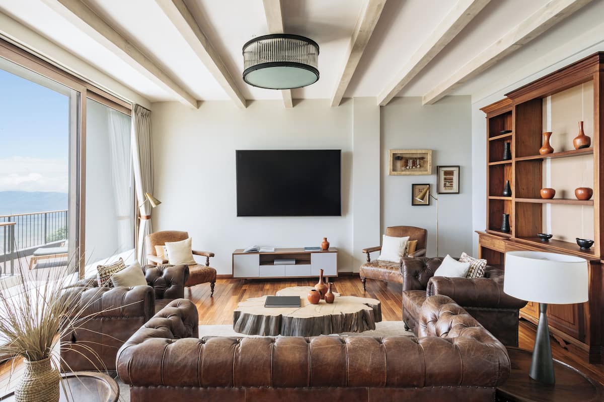A spacious living room with leather sofas, a coffee table, and a large flat-screen TV mounted on the wall.